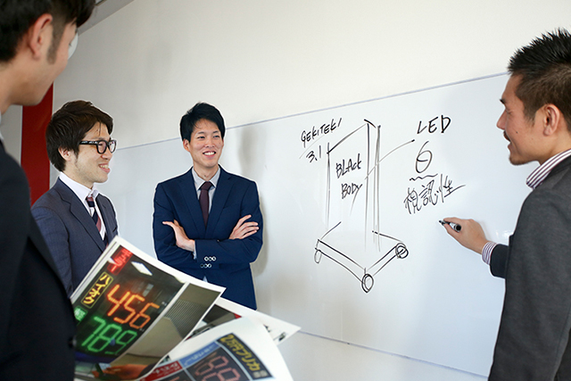 LED価格看板「ゲキテキ WINNING-L」本田課長がホワイトボードにイラスト書いてみんなで検討している画像